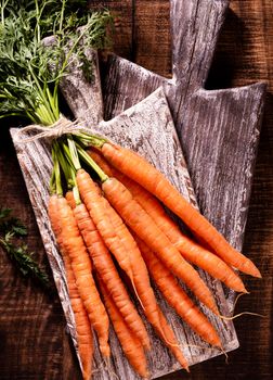 Organic carrot on wood cutting board, closeup photo.