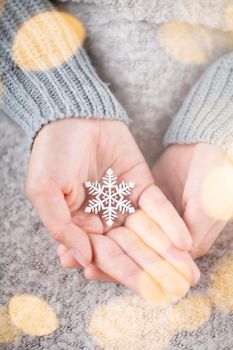 Winter Concept Young Hands Holding christmas decor.  Christmas decoration idea. Christmas decor in the hands of a woman, background with gold bokeh.