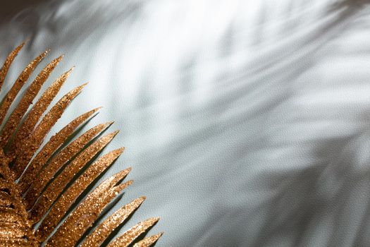 Gold palm leaves and shadows on a blue wall background.