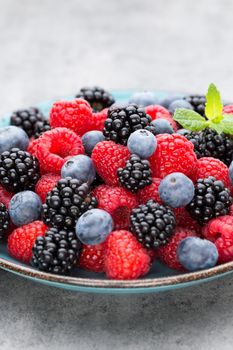 Fresh berries salad in a plate on a  wooden background. Flat lay, top view, copy space.