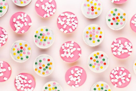 Multiple colorful nicely decorated muffins on a white background, top view.