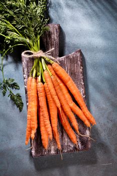 Organic carrot on wood cutting board, closeup photo.