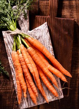 Organic carrot on wood cutting board, closeup photo.