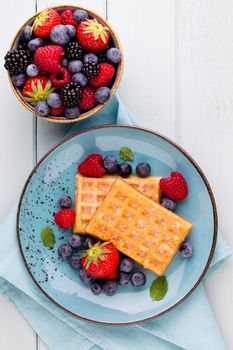 Fresh berries salad in a plate on a  wooden background. Flat lay, top view, copy space.