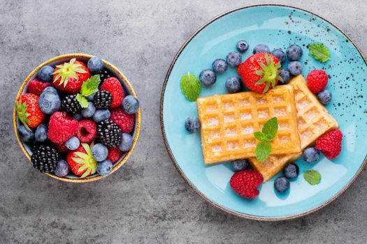 Fresh berries salad in a plate on a  wooden background. Flat lay, top view, copy space.