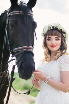 girl with red lips in a white dress near a black horse