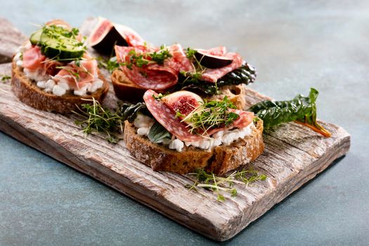 Variety of mini sandwiches with cream cheese, vegetables and salami. 