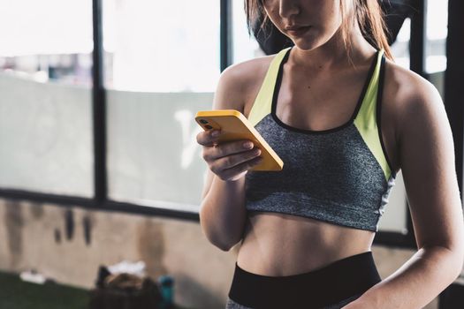 close up young fit woman using smart phone at gym.