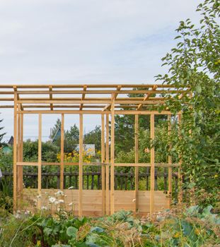 Wooden frame construction of a new veranda or gazebo on the territory of a country plot, in summer, outdoors.