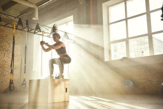 Working out. Side view of beautiful athletic woman in sportswear training legs at gym. Professional sport. Workout