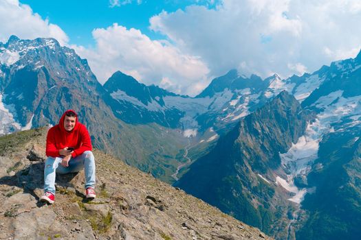 Male traveler using mobile phone against cloudy sky on sunny day in mountainous terrain.