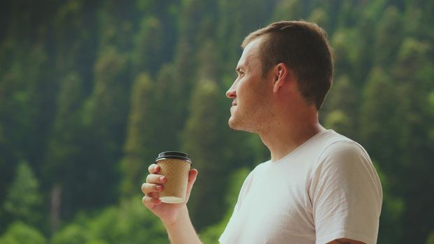 Adult male enjoying hot drink against mountain landscape.