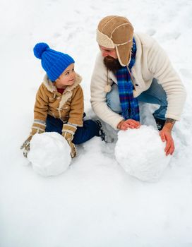 Happy father and son play on winter Christmas time. Father and son making snowman. Thanksgiving day and Christmas. Father and his son playing outdoors