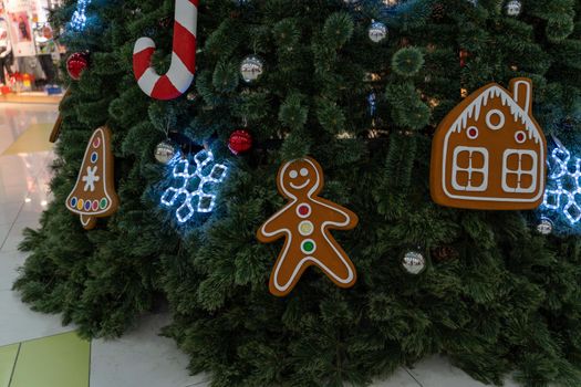 Close up of big Christmas tree with different christmas toys in shopping center. Coniferous tree with decorative adornments to create festive mood during holiday celebration