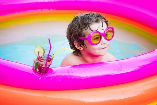 Cute kids relaxed and drink cocktail in swimming pool. Child boy and best swimming pool. Beach party. Healthy outdoor sport activity for children. Vacation at Paradise