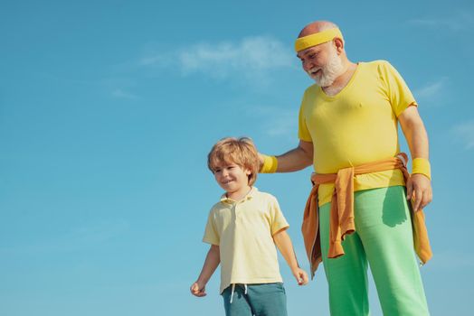 Grandfather giving grandson ride on back in park. Father and child training together. Sport yoga and fitness. Motivation and sport concept. Fathers day