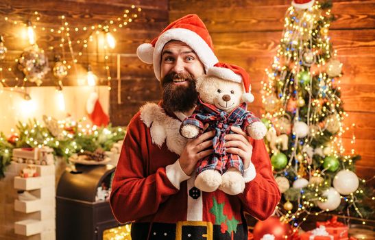 Crazy, funny Hipster Santa. Santa man posing with teddy on vintage wooden background