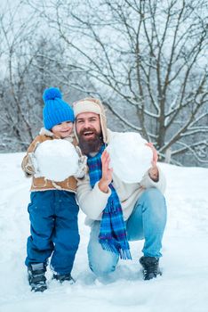 Best winter game for happy family. Happy father and son making snowman in the snow. Handmade funny snow man. Happy family plaing with a snowman on a snowy winter walk