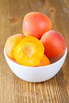 fresh ripe and juicy beautiful apricots in a bowl on a table, closeup, focus on one of the apricots, cut into half