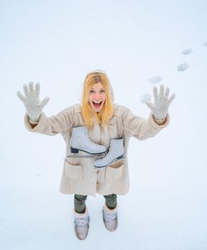 Girl playing with snow in park. Beautiful young woman laughing outdoors. Winter landscape background