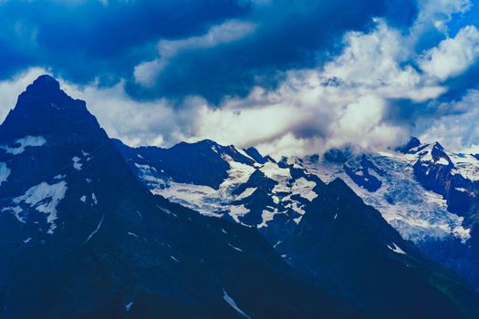 Mighty mountains with snow in cloudy weather.