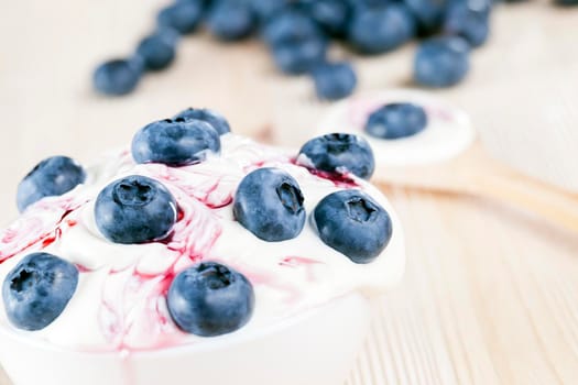 ripe blueberry berries lying on white creamy sauce during dessert cooking, closeup