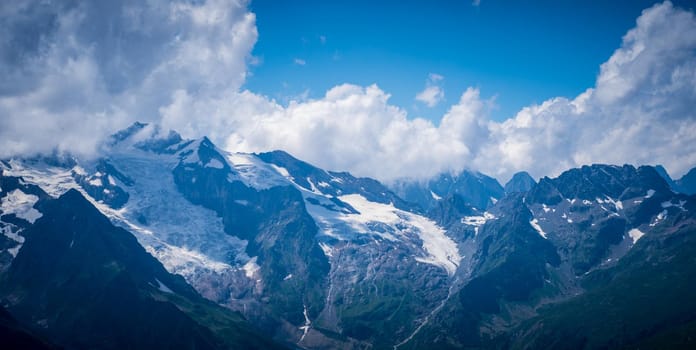 Mighty mountains with snow in cloudy weather.