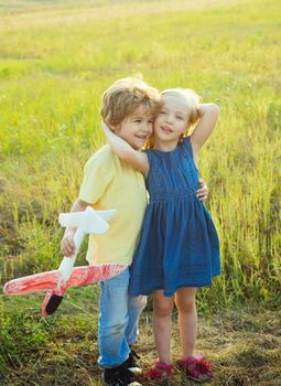 Cute children - daughter and son playing with toy airplane in the meadow in vintage color tone. Memories of childhood. Concept of dreams and travels. Valentine day