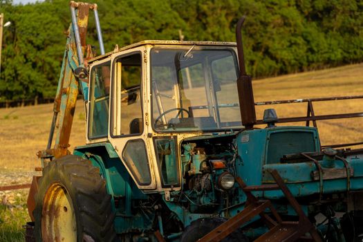 Weathered excavator digging ground during agricultural works in field on summer day in countryside