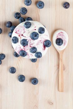 beautiful home cream of milk and fresh blueberries lying in a bowl and on a wooden table, wooden spoon, close-up, top view