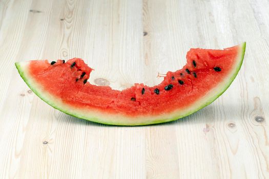 cut and bitten red juicy watermelon of a large size, the berry lies on a wooden table, close-up