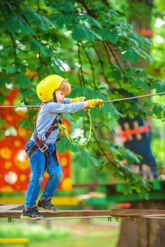 Cute school child boy enjoying a sunny day in a climbing adventure activity park
