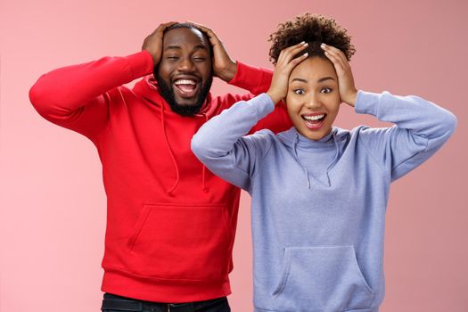 Waist-up happy charming surprised couple african american girlfriend boyfriend winning awesome gift lottery smiling impressed did not except win cannot believe luck grinning holding head shocked.