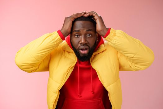 Shocked stupefied young african-american bearded man grab head drop jaw gasping confused frustrated looking upset troubled have problems standing stunned concerned pink background.