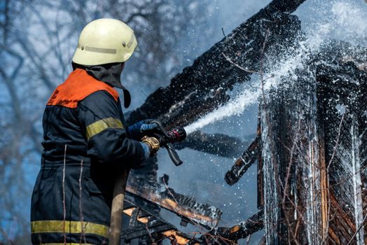 Fireman - men job. Firefighter are using water in fire fighting operation. Real brave hero combat the fire with foam extinguisher. Strong and brave firefighter saving burning building. Firefighter work concept