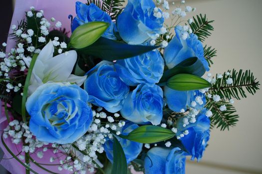 Close up of colorful bouquet of flowers. Flower composition of blue roses and white lilies in wrapping paper