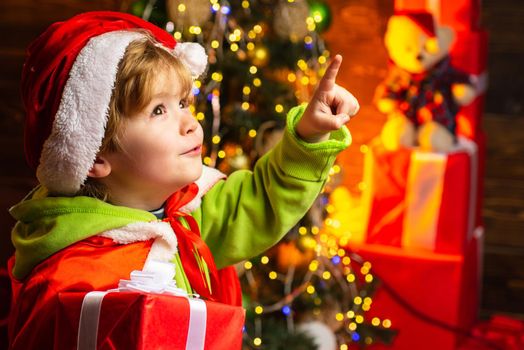 Boy cute child cheerful mood play near christmas tree. Gifts for winter holidays near fire place. Christmas eve. Kid at Christmas tree and fireplace on Xmas eve