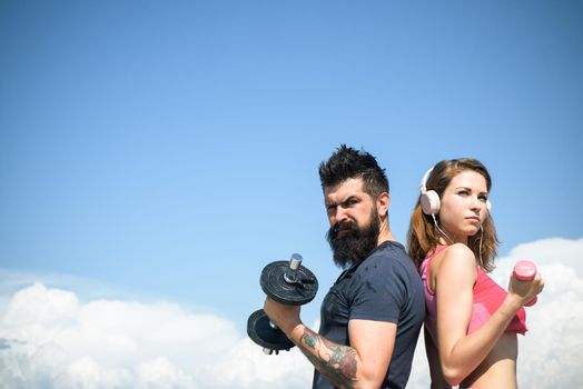 Young strong sporty couple working outside with sports equipment at beautiful blue summer sky background. Active lifestyle and sport activities concept