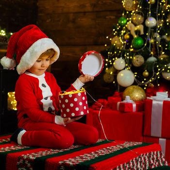 Merry and bright christmas. Lovely baby enjoy christmas. Childhood memories. Santa boy little child celebrate christmas at home. Family holiday. Boy cute child cheerful mood play near christmas tree.
