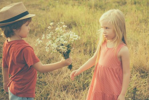 Childhood memories. Kids having fun in field against nature background. Beautiful little couple - boy and girl embracing. Kid having fun in spring field. Valentines day card. Festive Art Greeting Card