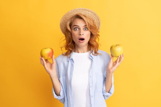 shocked young woman curly hair in summer straw hat with apple, detox.