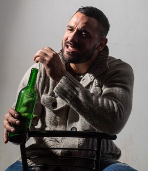Man holding a bottle on studio background. Brutal attractive bearded biker. Happy. Guy with beard drinking. Lifestyle people concept. Man with confident face and brutal style