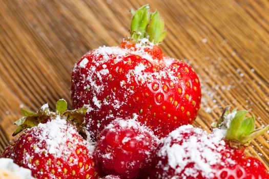 sprinkled with powdered sugar ripe red strawberry berries, lying on a wooden table while cooking