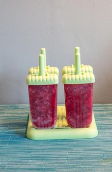 Homemade raspberry popsicles in a green mold during the summer heat.