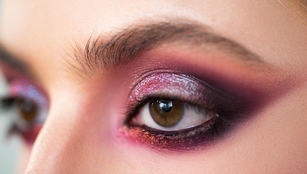 Purple smokey eyes makeup close up photo. Professional smokey eyes make up at beautiful girl for special occasion. Shiny glitter pigments in eyes make up. Luxury eye makeup concept