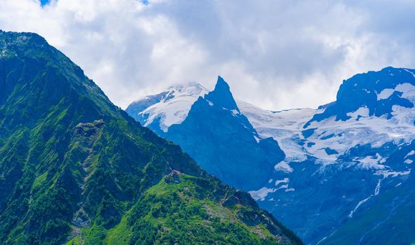 Glacier mountain with green vegetation on high ground in cloudy weather.