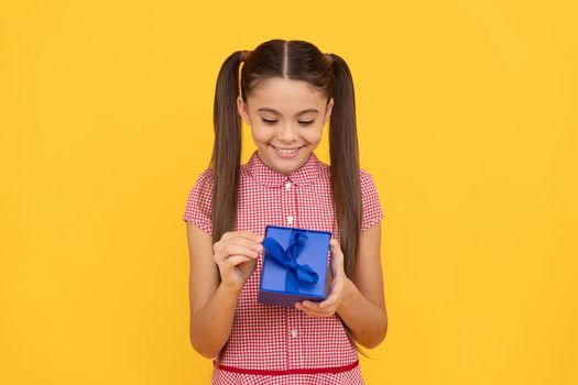 happy kid hold gift box on yellow background, present.