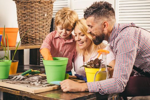 Happy family planting sprout in a plant pot. Little cute boy helps his parents. Teamwork and family togetherness concept. Environment protection and saving ecology starts from us