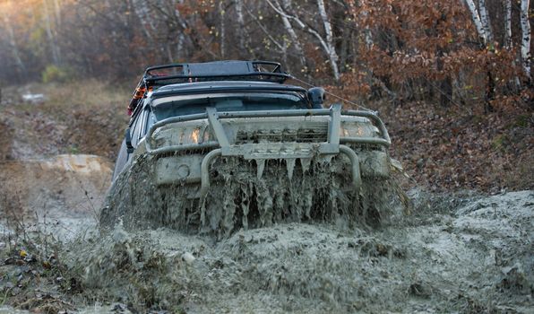 4x4 travel trekking. Track on mud. Off-road vehicle goes on the mountain. Mud and water splash in off road racing. Safari. Offroad. Adventure travel. Off-road travel on mountain road. Offroad vehicle coming out of a mud hole hazard