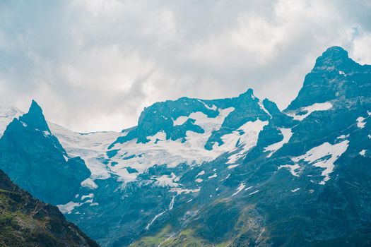 Mighty mountains with snow in cloudy weather.